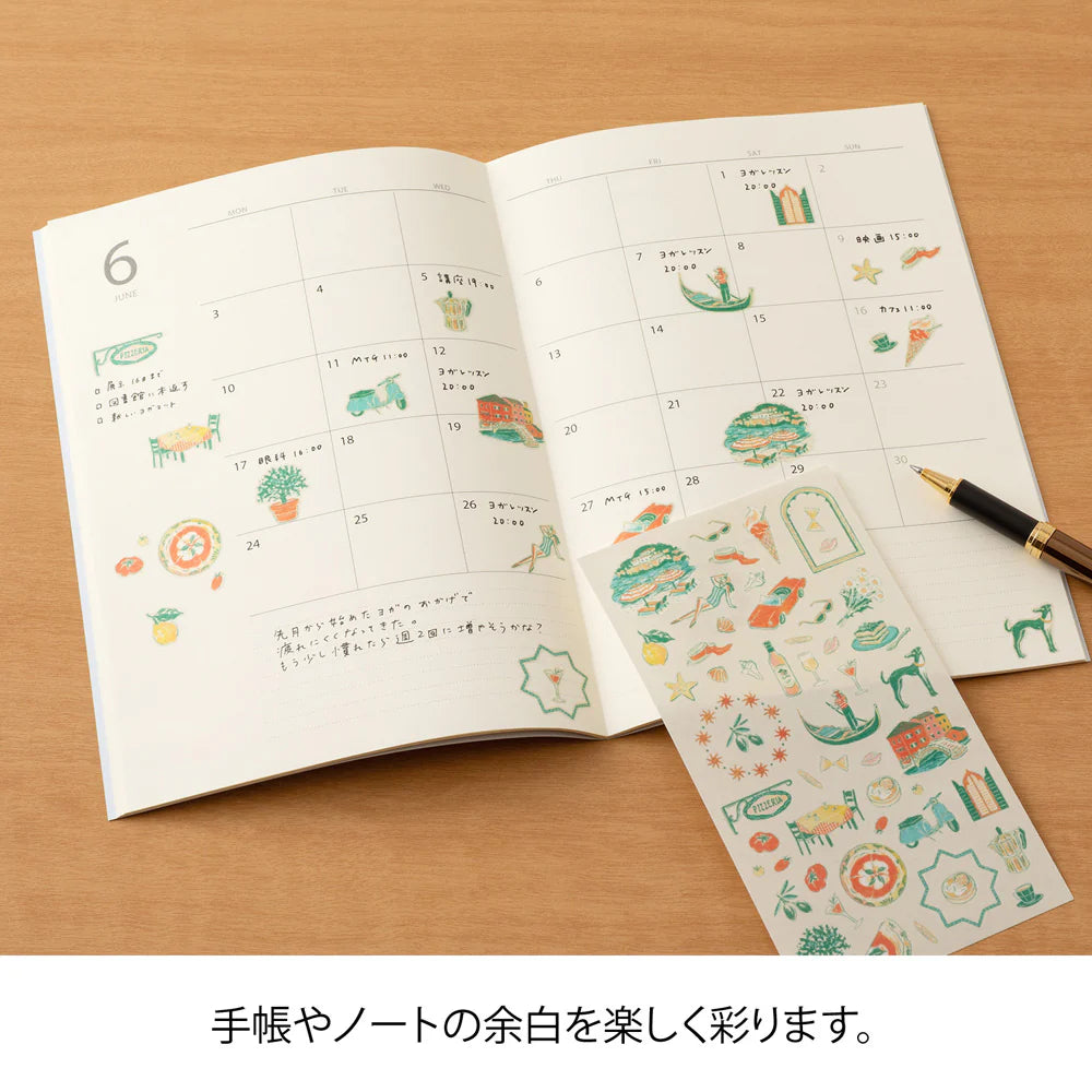 Open notebook with decorative stickers on a wooden surface