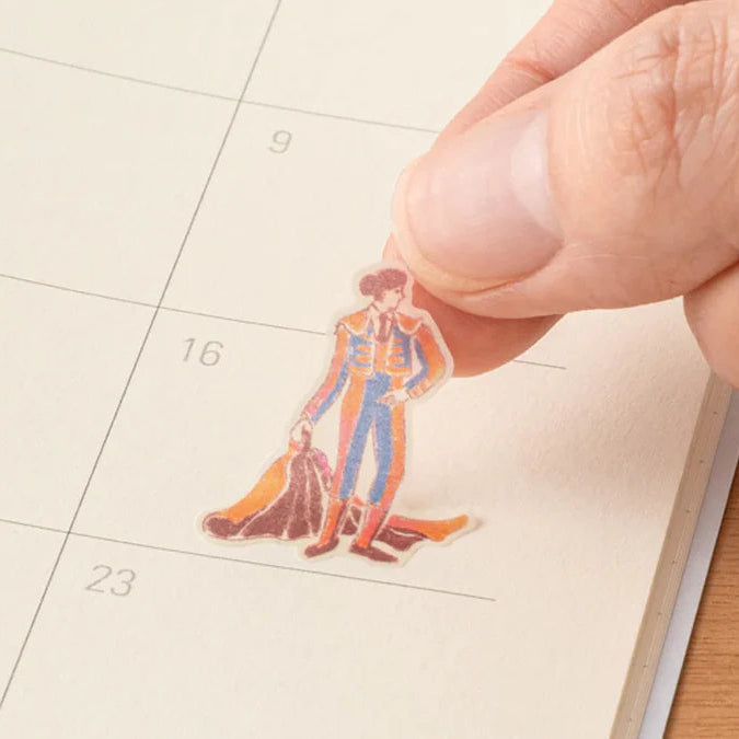 Hand placing a small illustrated Matador on a calendar page